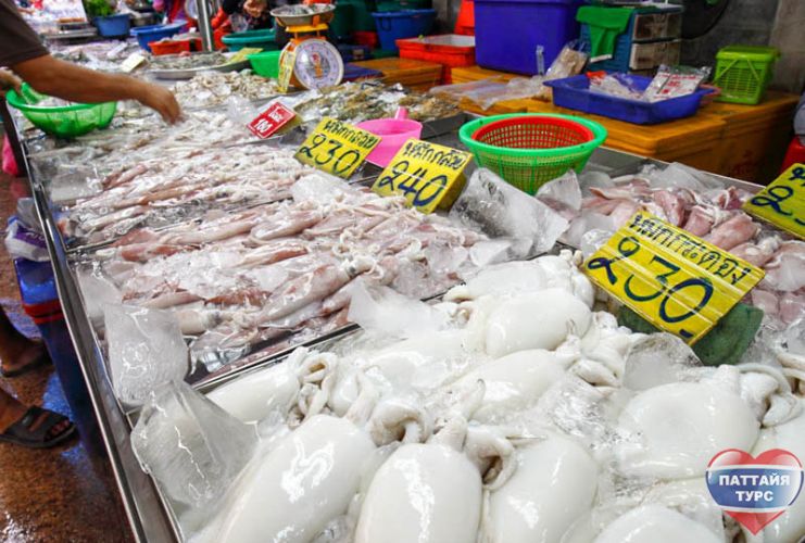 Продавец кальмаров на рынке морепродуктов в Паттайе