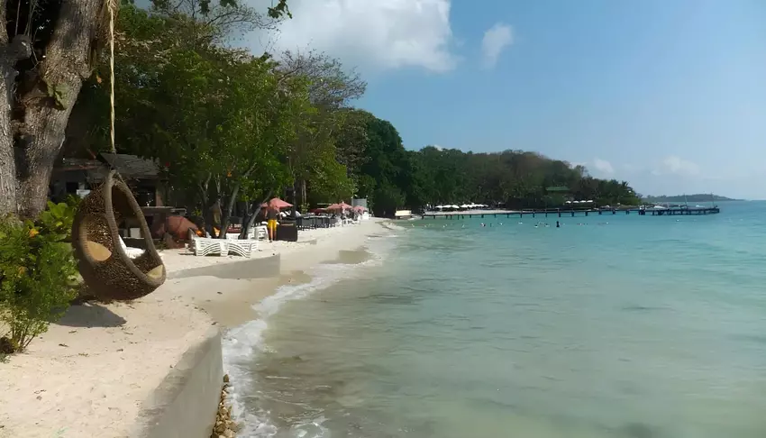 Пляж с белоснежным песком и прозрачной водой, лежаки и зелеными деревь